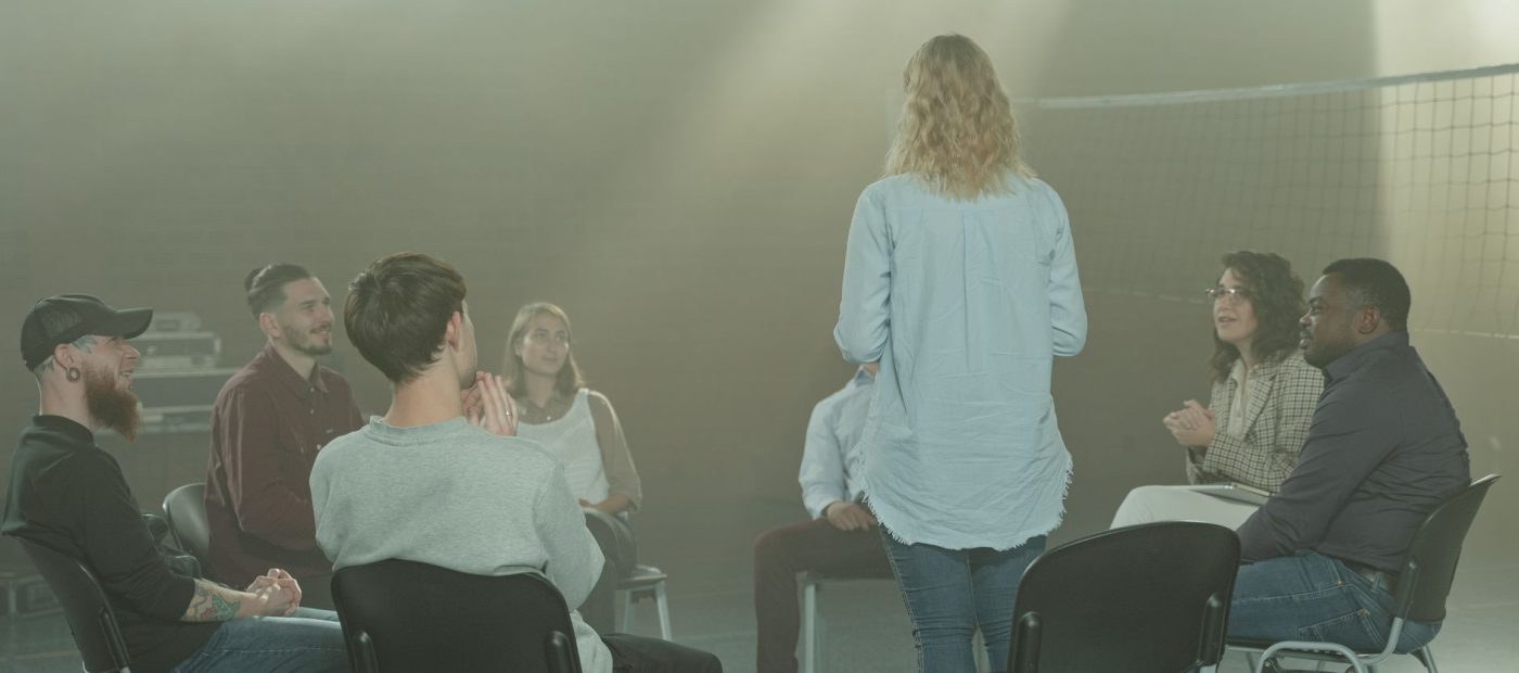 A diverse group in a therapy session indoors with a soft, smoky atmosphere.