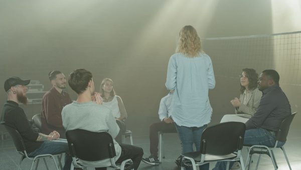 A diverse group in a therapy session indoors with a soft, smoky atmosphere.